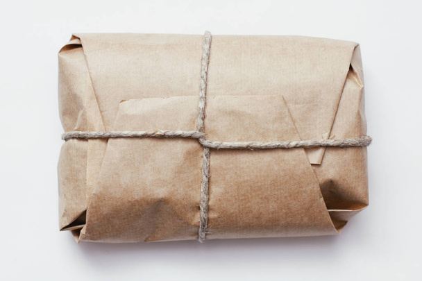 Box parcel wrapped in brown craft paper  tied hemp cord on white background.  - Foto, Imagen