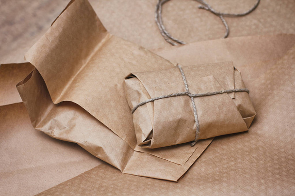 Parcel package wrapped with brown craft paper tied rope. Boxing process.  - Фото, изображение