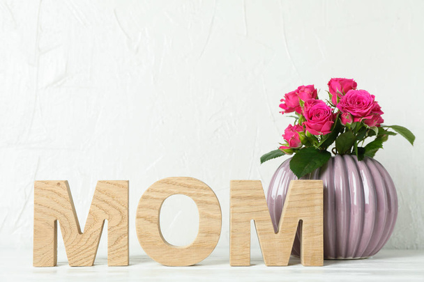 Inscrição Mãe e vaso com rosas rosa na mesa branca, espaço f
 - Foto, Imagem