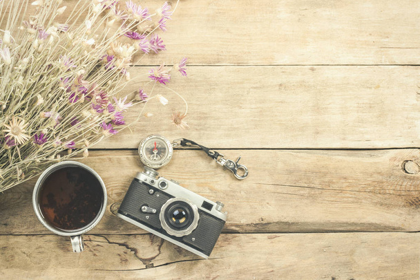 Wildflowers, metal cup of tea, a compass and other attributes for a hike on a wooden background. Concept of hiking in the mountains or the forest, tourism, tent rest, camp. Flat lay, top view. - Photo, Image