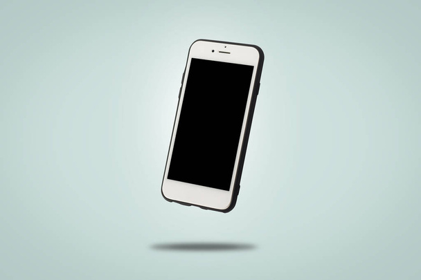 fliegendes weißes Handy auf blauem Hintergrund. Schweben. Konzeptanwendungen für Telefon, Mobilgerät, Präsentation. - Foto, Bild