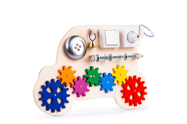 Umweltfreundliches Holzbrett - Lernspielzeug für Kinder, Babys auf weißem, isoliertem Hintergrund, bestehend aus Taschenlampe, Schalter, Perlen, Gang, Glocke, Rosette. - Foto, Bild