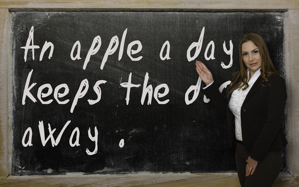 Tanár egy napra egy almát mutatja tartja az orvost távol blackboa - Fotó, kép