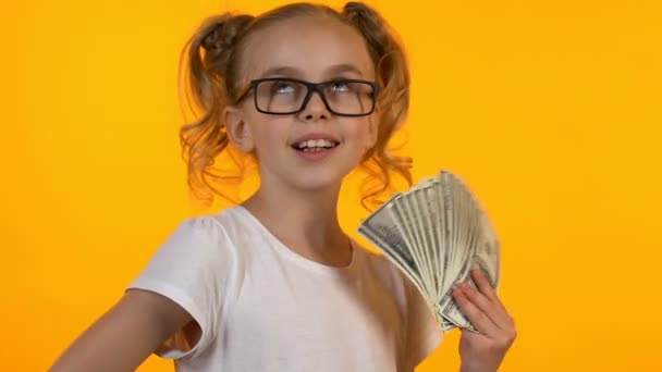 Blond little kid in eyeglasses holding bunch of dollars, first money good income - Imágenes, Vídeo