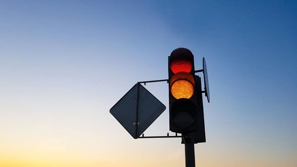 Traffic light with red and yellow signals on blue sky background - 写真・画像