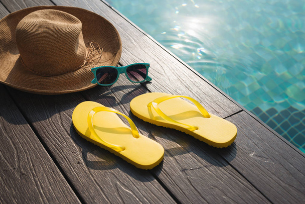 Chapeau, lunettes de soleil et tongs près de la piscine
 - Photo, image