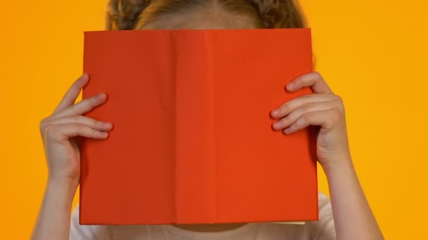 Little smart kid in eyeglasses reading encyclopedia shocked by interesting facts - Filmati, video