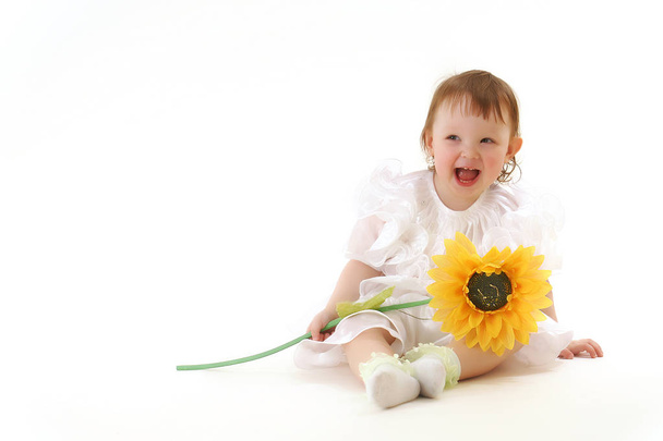 kleines fröhliches lachendes Baby beim Spielen mit Sonnenblumen - Foto, Bild