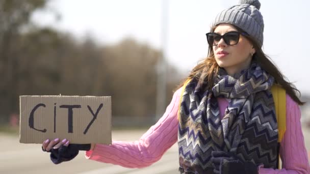 Ελκυστική νεαρή γυναίκα ωτοστόπ προσπαθήσει να πάρει την πόλη με αφίσα  - Πλάνα, βίντεο