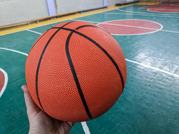 Баскетбол. Баскетбольная площадка. Рука держит мяч
 - Фото, изображение