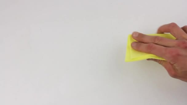 emberi kéz darabos és megtisztítja az asztal fehér felületét sárga kendővel - Felvétel, videó