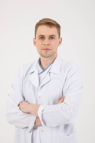 Medical staff. Young sympathetic doctor stands isolated on a white background dressed in a uniform for doctors - Zdjęcie, obraz