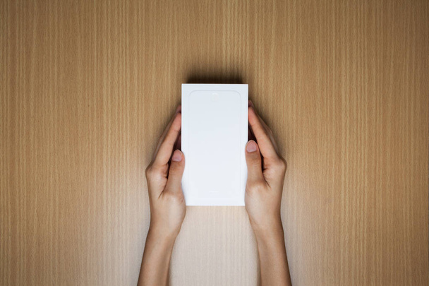 A female(woman) hands hold a empty(blank) white box on the desk - Fotoğraf, Görsel