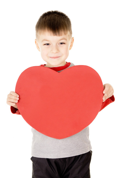 a small child stands and holds the heart - Foto, Imagen