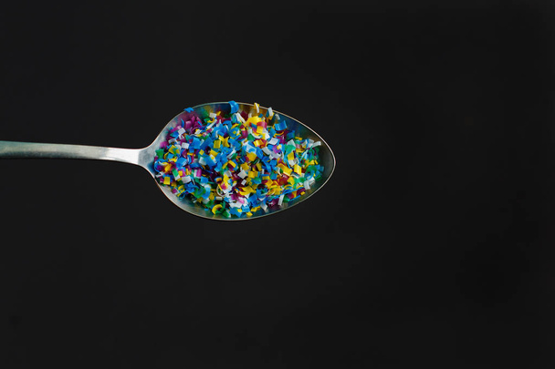 Microplastic in spoon on black background . Threat to human health and environment Dangerous additives Toxic substances. - Photo, Image