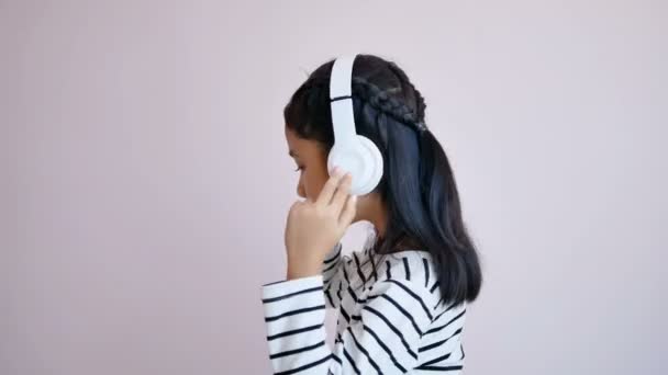 Kinderen luisteren naar muziek met behulp van witte hoofdtelefoon en schommelen volgens het ritme van de muziek - Video