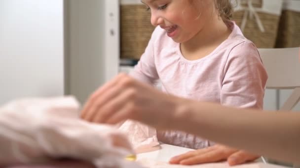 Mom and her little daughter do needlework together. Girl with scissors cuts the cloth for DIY - Záběry, video