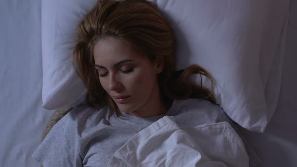 Beautiful lady lying in bed at night, cozy healthy sleep on comfortable mattress - Felvétel, videó