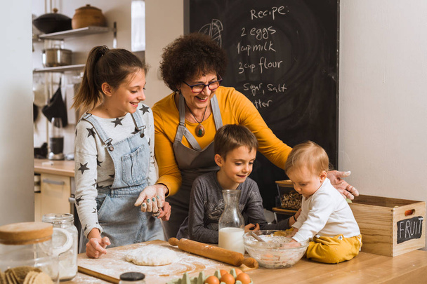 Senior woman with grandchildren cooking in kitchen together - Fotoğraf, Görsel