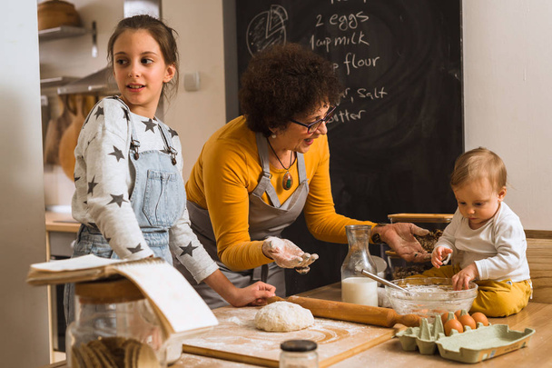 senior woman and her grandchildren baking together in kitchen - Fotografie, Obrázek