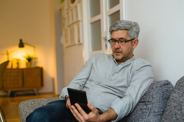 Mature man using digital tablet at home - Foto, Imagem
