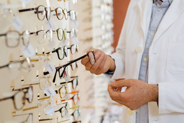 closeup of optician hands holding eyeglasses in optic store - Foto, afbeelding