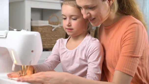 Mom teaching her little daughter to sew using a sewing machine in the nursery at home - Filmmaterial, Video