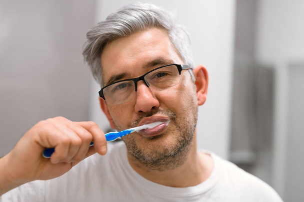 Sleepy man brushing teeth in bathroom - Foto, Imagem