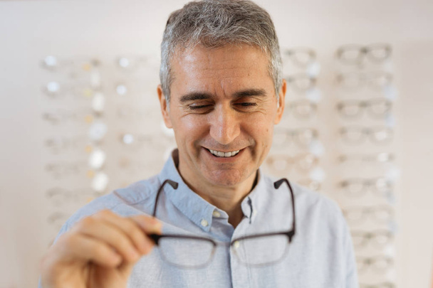 Closeup of man holding eyeglasses toward camera - Foto, Bild