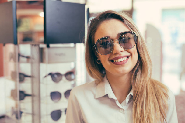 Young woman wearing sunglasses in optic store - Fotó, kép