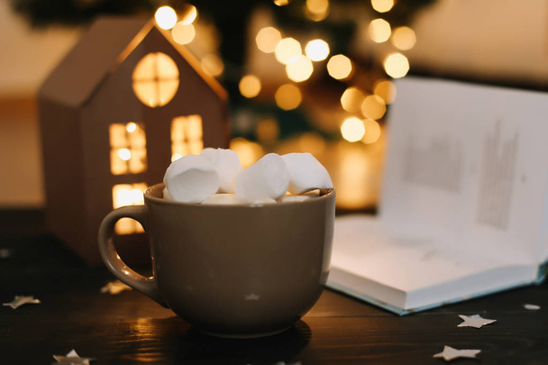 Coffee cup with marshmallows and a book on the table. Still life on dark background. - Foto, Bild