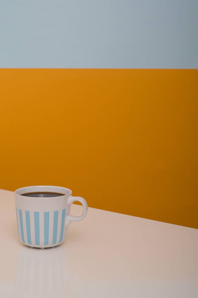 Coffee in white mug with blue stripes on beige, grey and orange background - Foto, Imagem