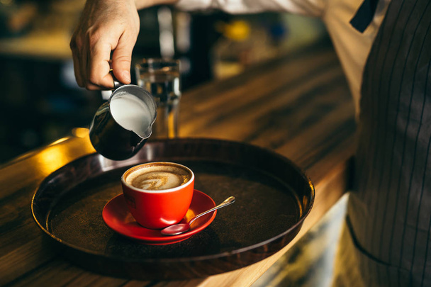 Man pouring milk in coffee at cafe - Photo, Image