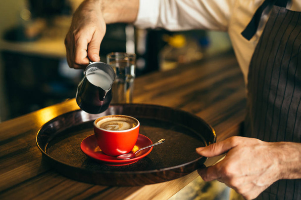 Man pouring milk in coffee at cafe - Valokuva, kuva