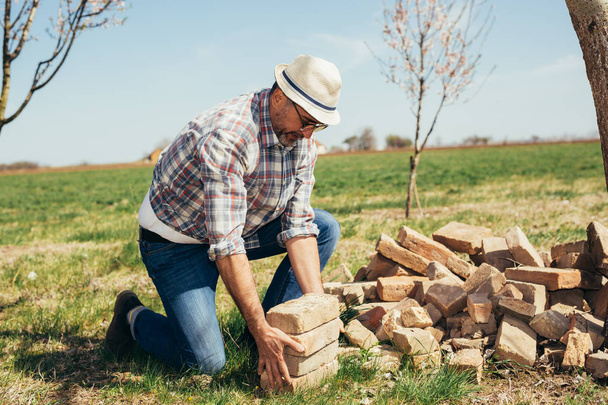 Mature man holding bricks outdoor - Foto, immagini