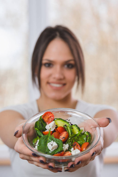 Portrait of young woman in showing salad at camera - Photo, Image