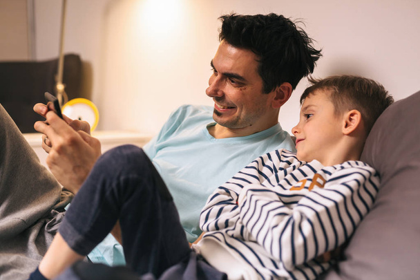 father and son playing games on tablet at home - Valokuva, kuva