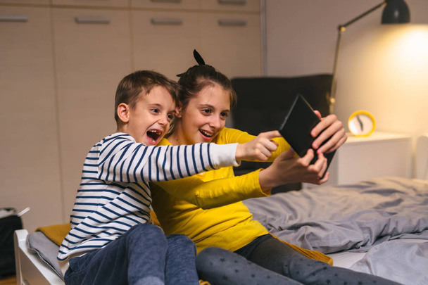 brother and sister playing games on tablet at home - Fotoğraf, Görsel
