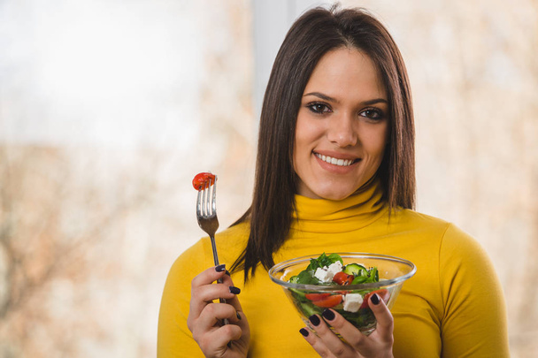 Mosolyogva csinos nő gazdaság saláta és nézte kamera - Fotó, kép