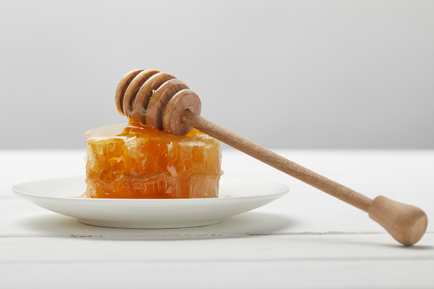 plate with honey dripper and delicious honeycomb on white wooden table isolated on grey - Foto, afbeelding