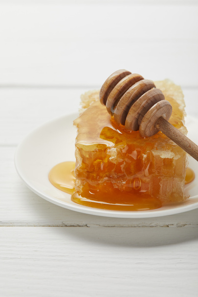 Selective Focus of plate with honey dripper and delicious honeycomb on white wooden table - Zdjęcie, obraz