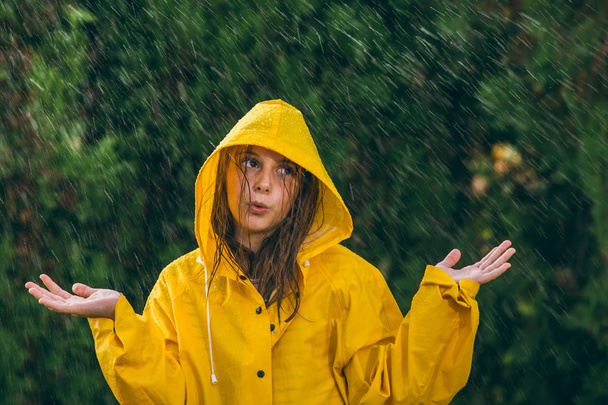 Κορίτσι με κίτρινο αδιάβροχο που διασκεδάζει στη βροχή - Φωτογραφία, εικόνα