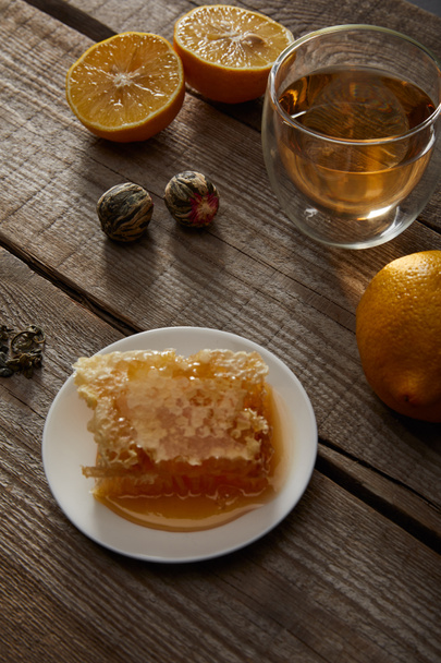 pohár hagyományos kínai virágzó tea, citrom és méhsejt a fából készült asztal  - Fotó, kép