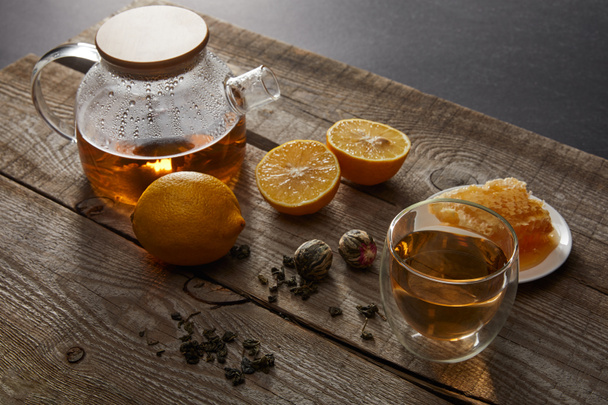 cytryny, plaster miodu i przezroczysty czajniczek z kieliszek chińskiej kwitnącej herbaty na powierzchni drewnianej - Zdjęcie, obraz