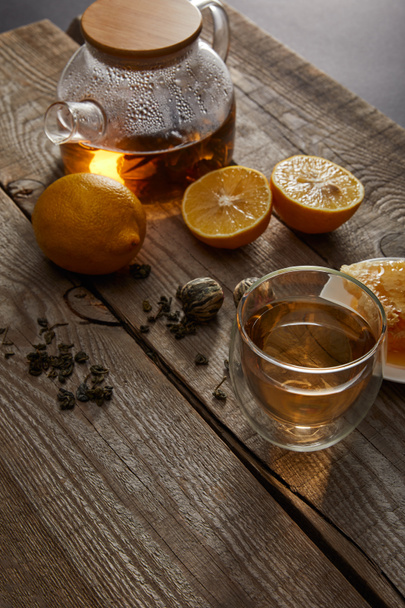 citrony, čajové míče a průhledná Čajová konvice se sklenicí tradičního čínského Kvetoucí čaje na dřevěné ploše - Fotografie, Obrázek