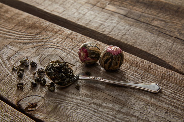 cuchara con té verde y bolas de té en flor en la mesa de madera
 - Foto, Imagen