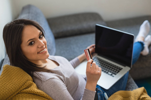 Nainen käyttää kannettavaa tietokonetta ja ostoksia verkossa kotoa
 - Valokuva, kuva