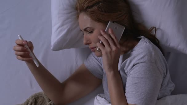 Crying woman holding pregnancy test and talking phone in bed, negative result - Felvétel, videó