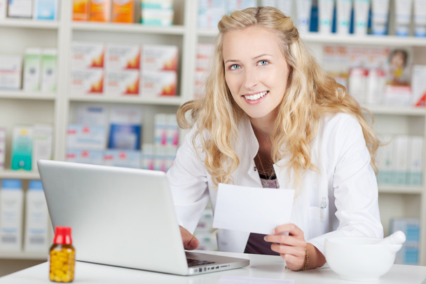 Pharmacist Holding Prescription Paper While Using Laptop At Coun - Фото, изображение