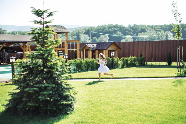 Menina jogando em um grande quintal de casa de madeira
 - Foto, Imagem